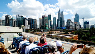 Passengers happily seated in the comfortable Hop-on Hop-off bus, capturing the picturesque cityscape while enjoying their journey.